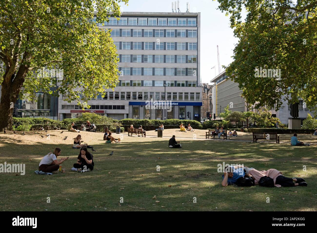 Des gens assis sur l'herbe et manger à Cavendish Square, Marylebone, City of Westminster, London England Angleterre UK Banque D'Images