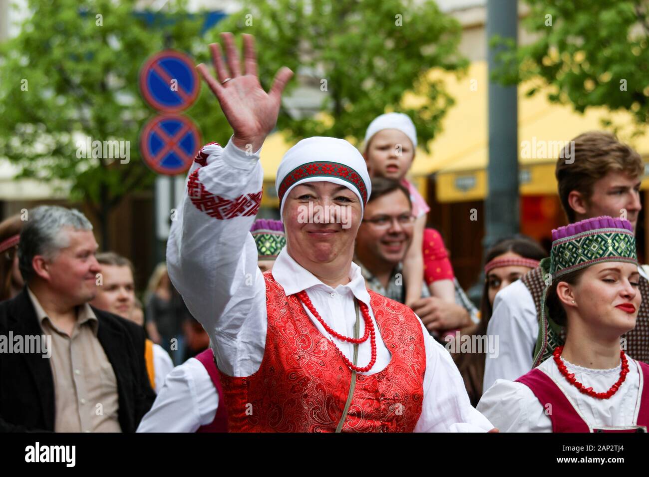Femme d'âge moyen en costume de parade de spectateurs agitant à Vilnius, Lituanie Banque D'Images