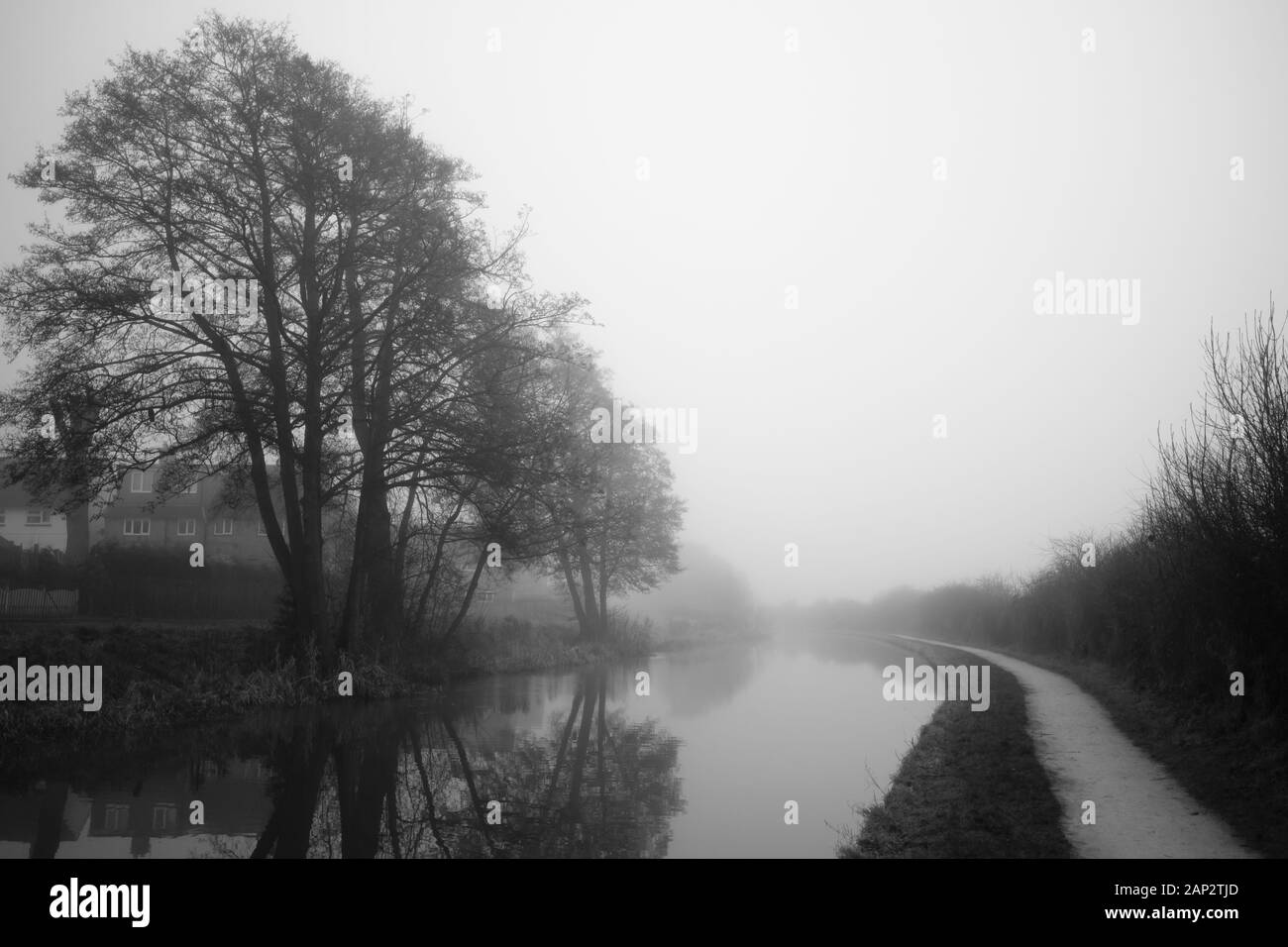 Tôt le matin malté par le canal Trent et Mersey (Staffordshire, Royaume-Uni). Reflet des arbres sans feuilles dans l'eau. Sentier qui va à l'éternité Banque D'Images