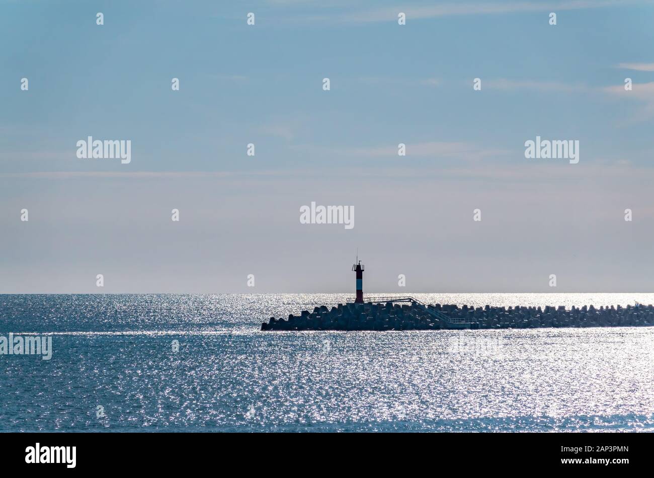 Ciel clair et lumineux, coucher de soleil sur la mer avec un brise-lames et un phare. Arrière-plan de l'espace de copie Banque D'Images