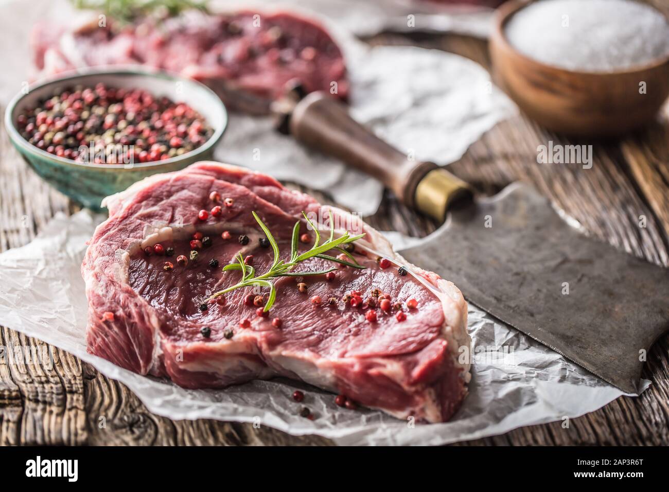 Bifteck de faux-filet de boeuf avec sel poivre et romarin sur table en bois Banque D'Images