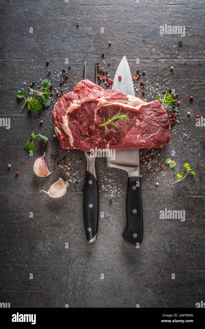 Steak de boeuf avec fourchette et couteau sel poivre et herbes sur fond de béton foncé Banque D'Images