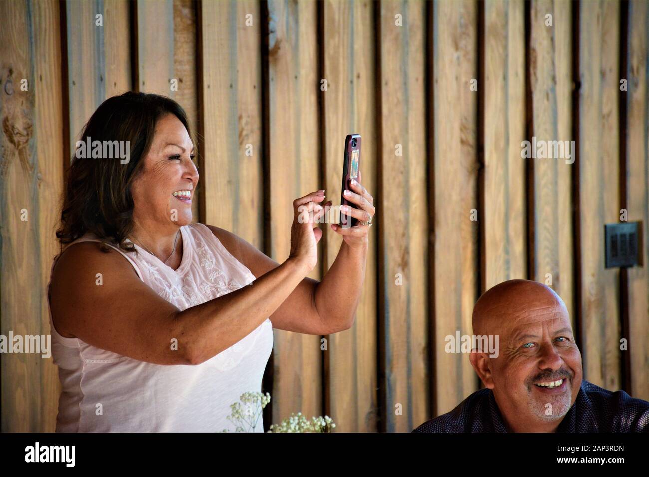 Bonne femme d'âge moyen faisant une photo de téléphone cellulaire à une réunion de famille avec un sourire Banque D'Images