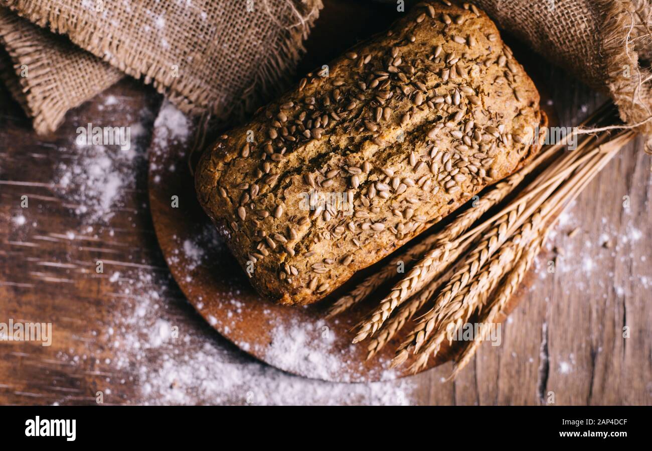 Vue sur le pain fait maison avec du blé entier sur une table en bois vintage. Préparation d'aliments biologiques sains d'en haut. Banque D'Images