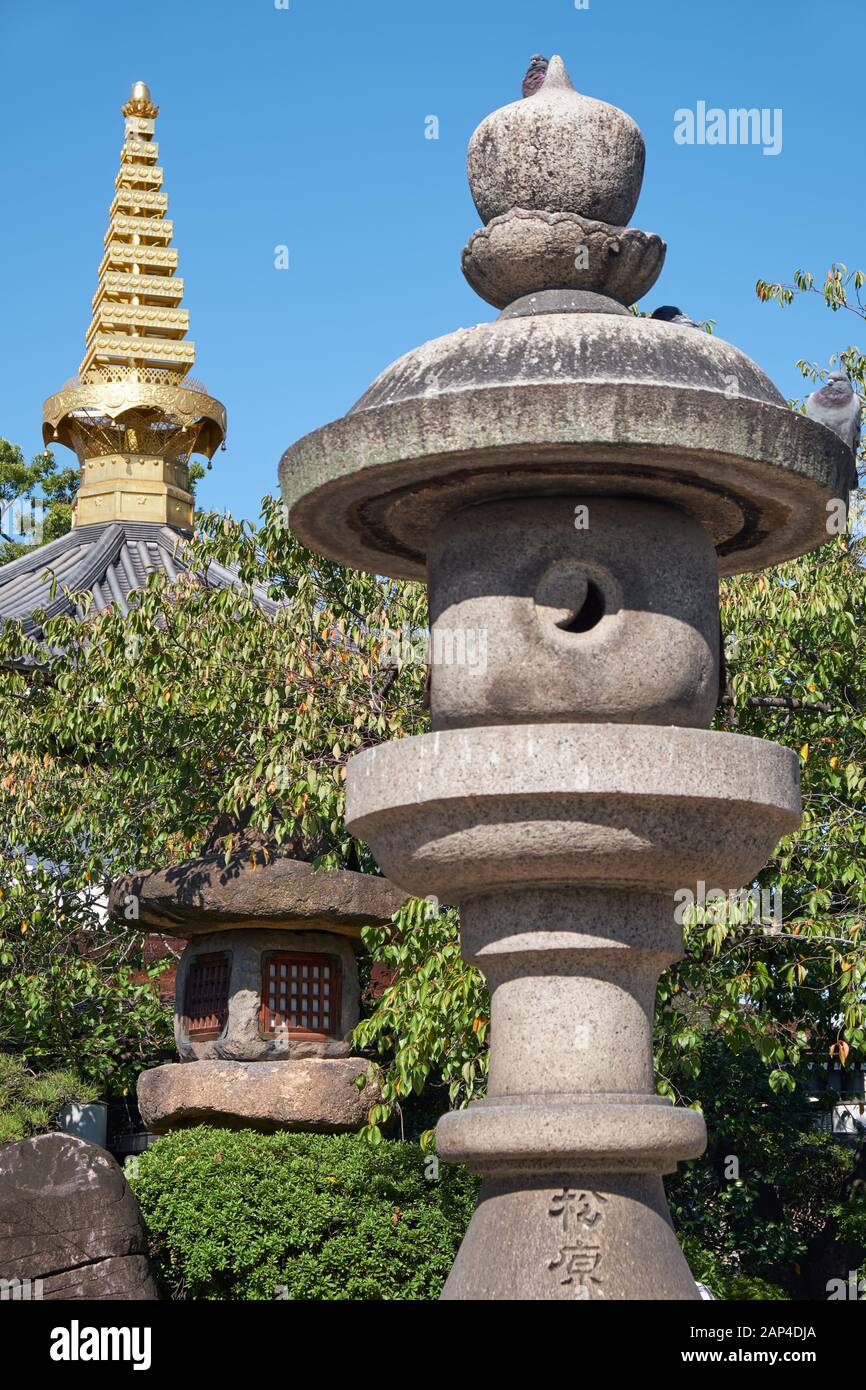 La vue des lanternes en pierre traditionnelles (Tachidoro) avec la pointe de la pagode (sorin) sur le fond dans le temple Isshin-ji. Osaka. Japon Banque D'Images