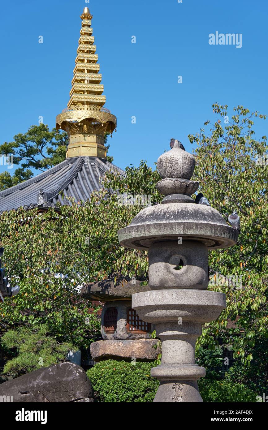 La vue des lanternes en pierre traditionnelles (Tachidoro) avec la pointe de la pagode (sorin) sur le fond dans le temple Isshin-ji. Osaka. Japon Banque D'Images