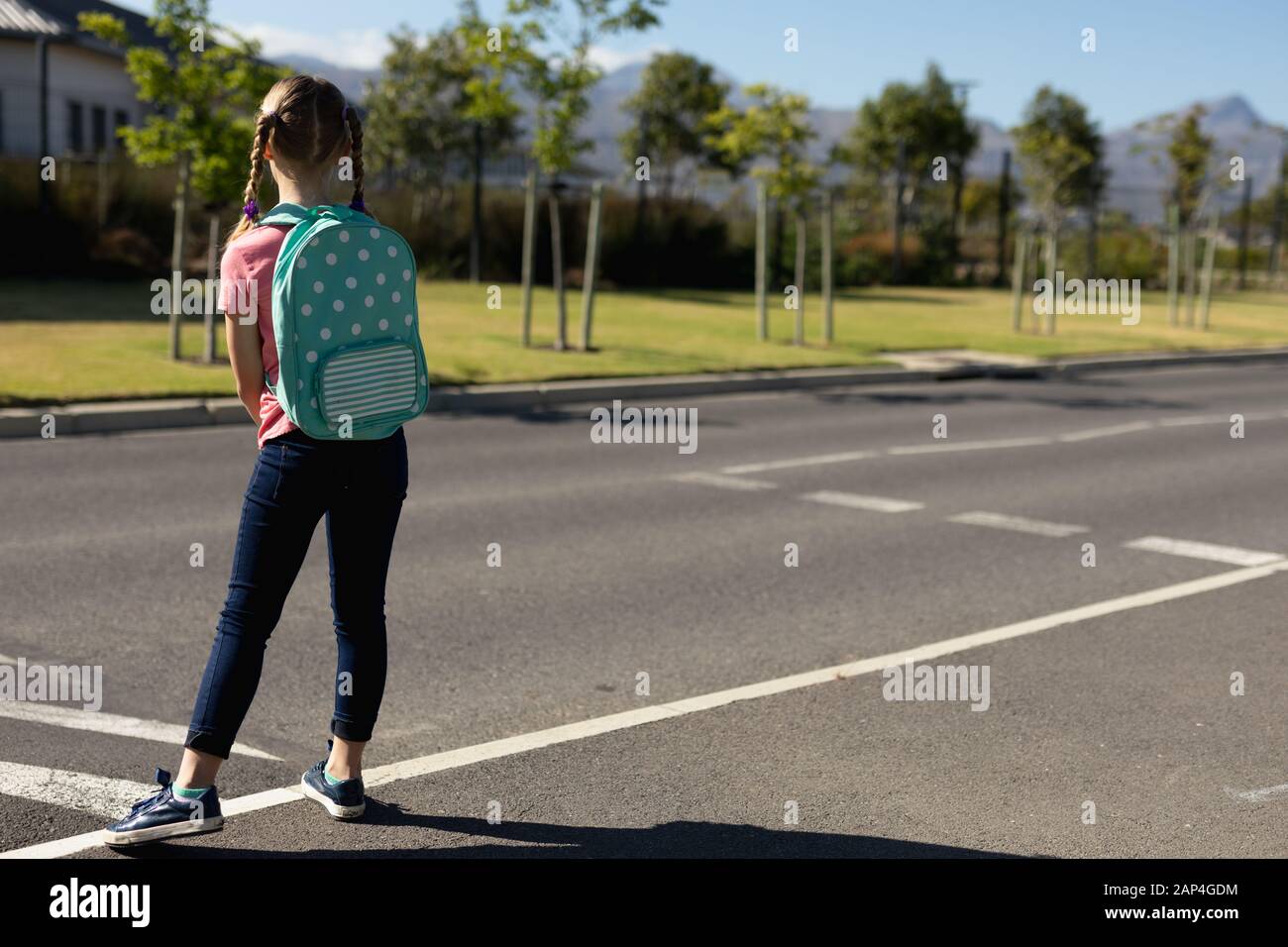 Écolière à la recherche de la circulation tout en attendant de traverser la route Banque D'Images