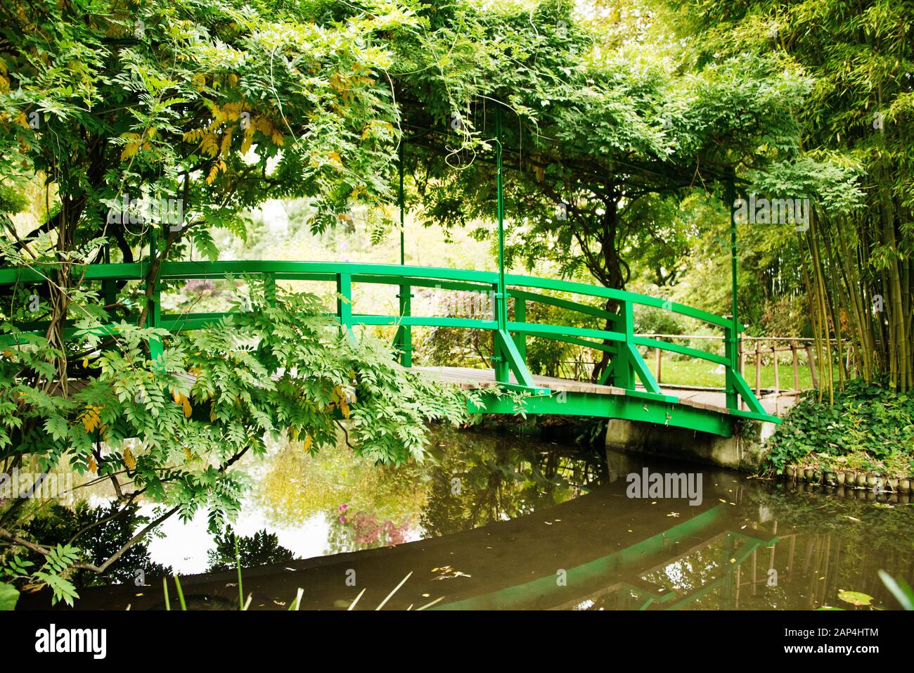 Claude Monet Jardin Giverny. Pont japonais avec arbres en premier plan et pont couvert Banque D'Images