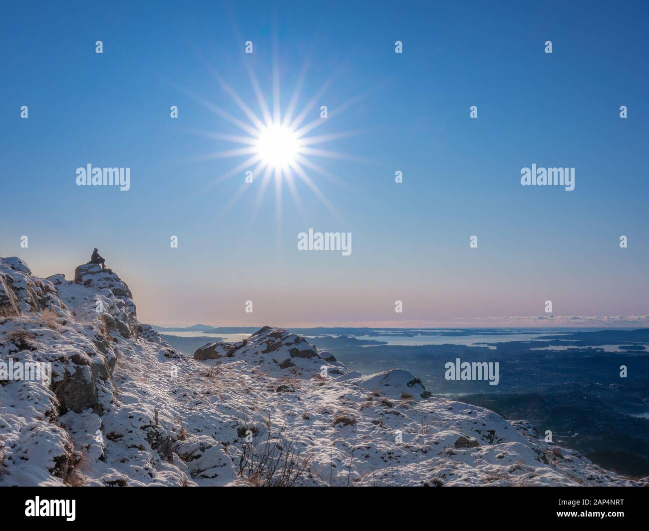 Silhouette personne assise sur le rocher au sommet de la montagne dans le paysage d'hiver. Beaucoup de neige et belle vue panoramique tranquille sur les fjords en bas du m Banque D'Images