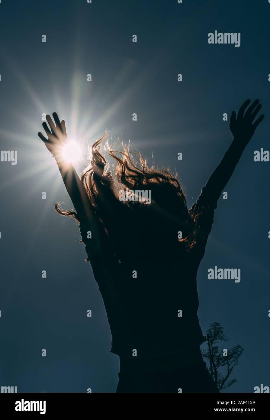 Silhouette de jeune femme levant les mains avec joie vers le soleil. Image sombre et bas angle de Happy unreconnaissable fille Banque D'Images Silhouette de jeune femme levant les mains avec joie vers le soleil. Image sombre et bas angle de Happy unreconnaissable fille Banque D'Images