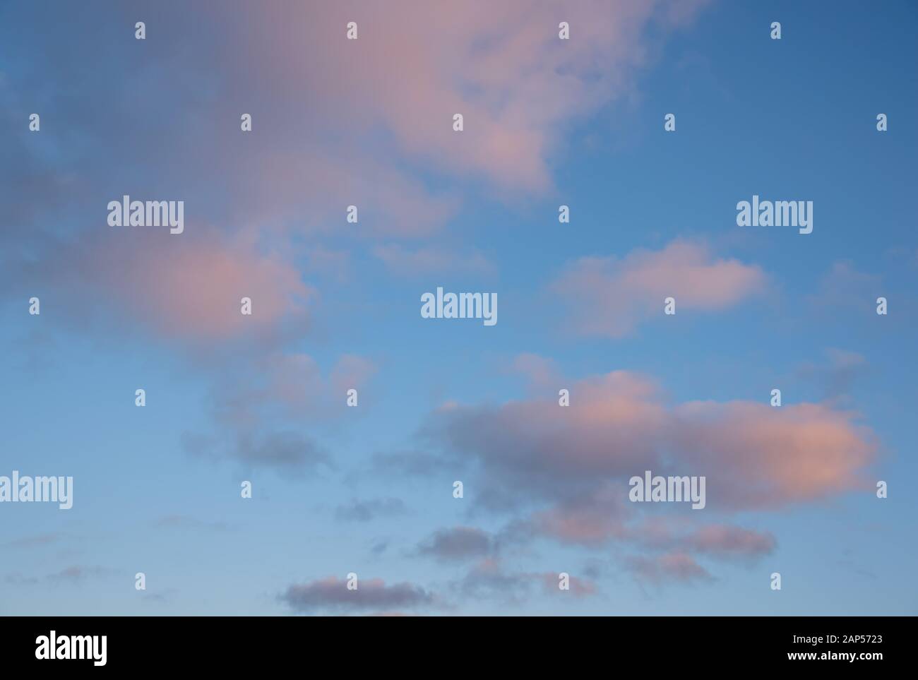 Vanille rose nuages sur un fond bleu ciel de coucher du soleil. Banque D'Images