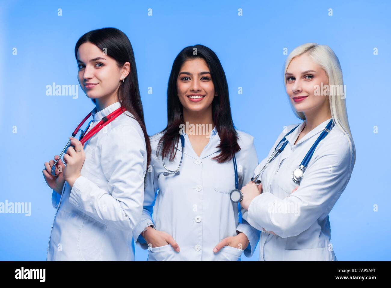 Une équipe de jeunes médecins. Multinationale - médecin, infirmière et chirurgien dans le fond bleu. Un groupe d'étudiants en médecine de différentes nationalités a Banque D'Images