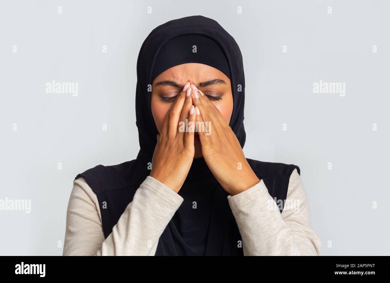 Une femme musulmane noire bouleversée dans le hijab couvrant le visage avec les mains Banque D'Images
