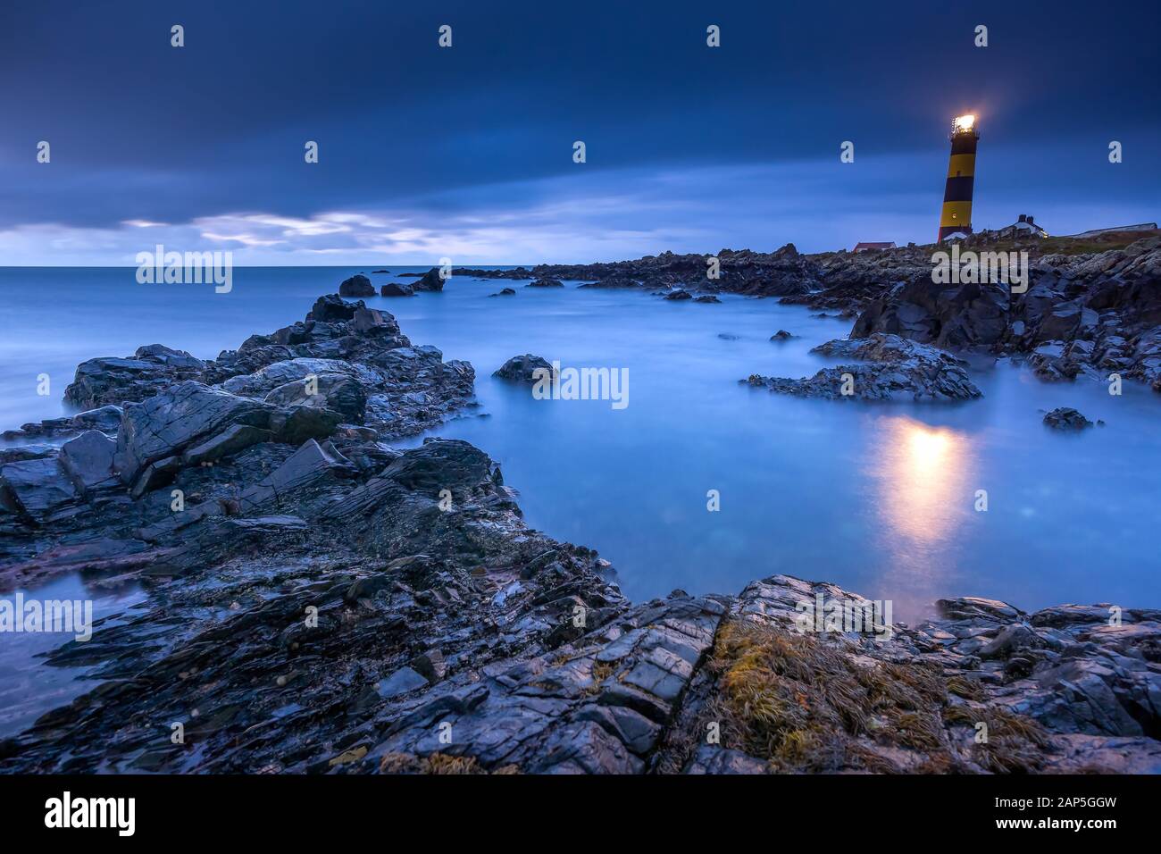 Twilight commence à se rendre à la lumière du jour au phare de St. Johns point. Littoral rocheux avec eau et ciel flouté, photographie à longue exposition Banque D'Images