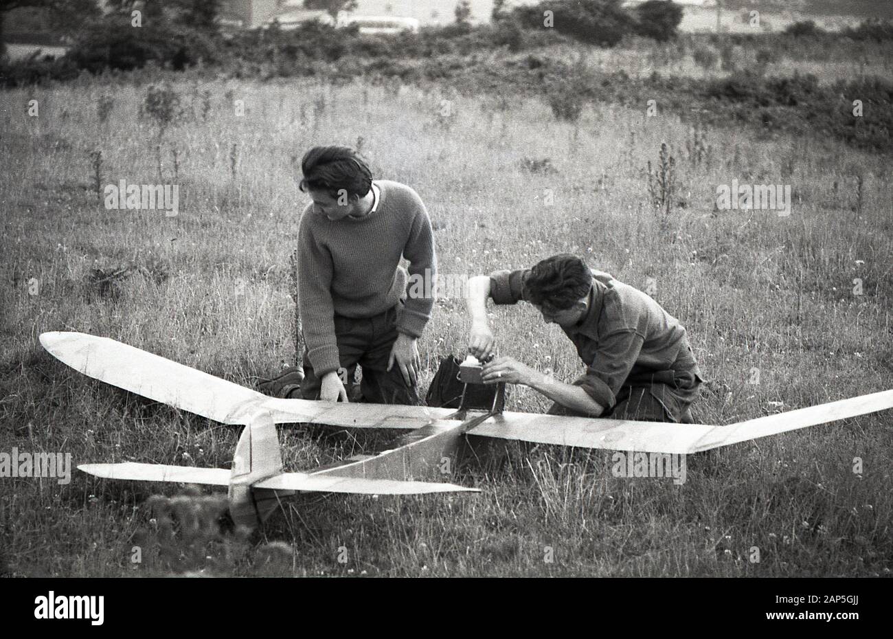 Années 1950, historique, deux jeunes hommes, passionnés de vol dans un champ avec leur planteur en bois fait maison, Angleterre, Royaume-Uni. Les dorures n'ont pas de moteur et ces avions non alimentés utilisent des courants naturels de montée de l'air dans l'atmosphère pour obtenir l'attitude. Le sport était une activité de loisirs et de loisirs populaire à cette époque. Banque D'Images