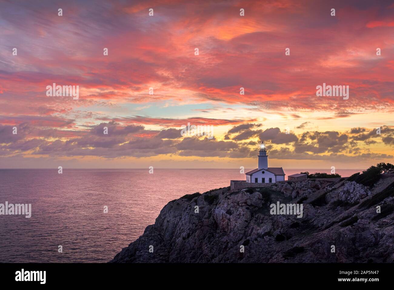 Phare de Far de Capdepera, lever du soleil avec beau ciel coloré et phare lumière faisceau, Cala Ratjada, Majorque, Espagne. Banque D'Images