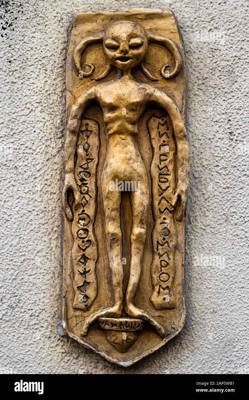 Ancienne statuette dorée en forme d'humanoïde mythique. Vieille figurine étrangère sur le mur avec des symboles étranges et mystérieux. Produit d'argile Banque D'Images