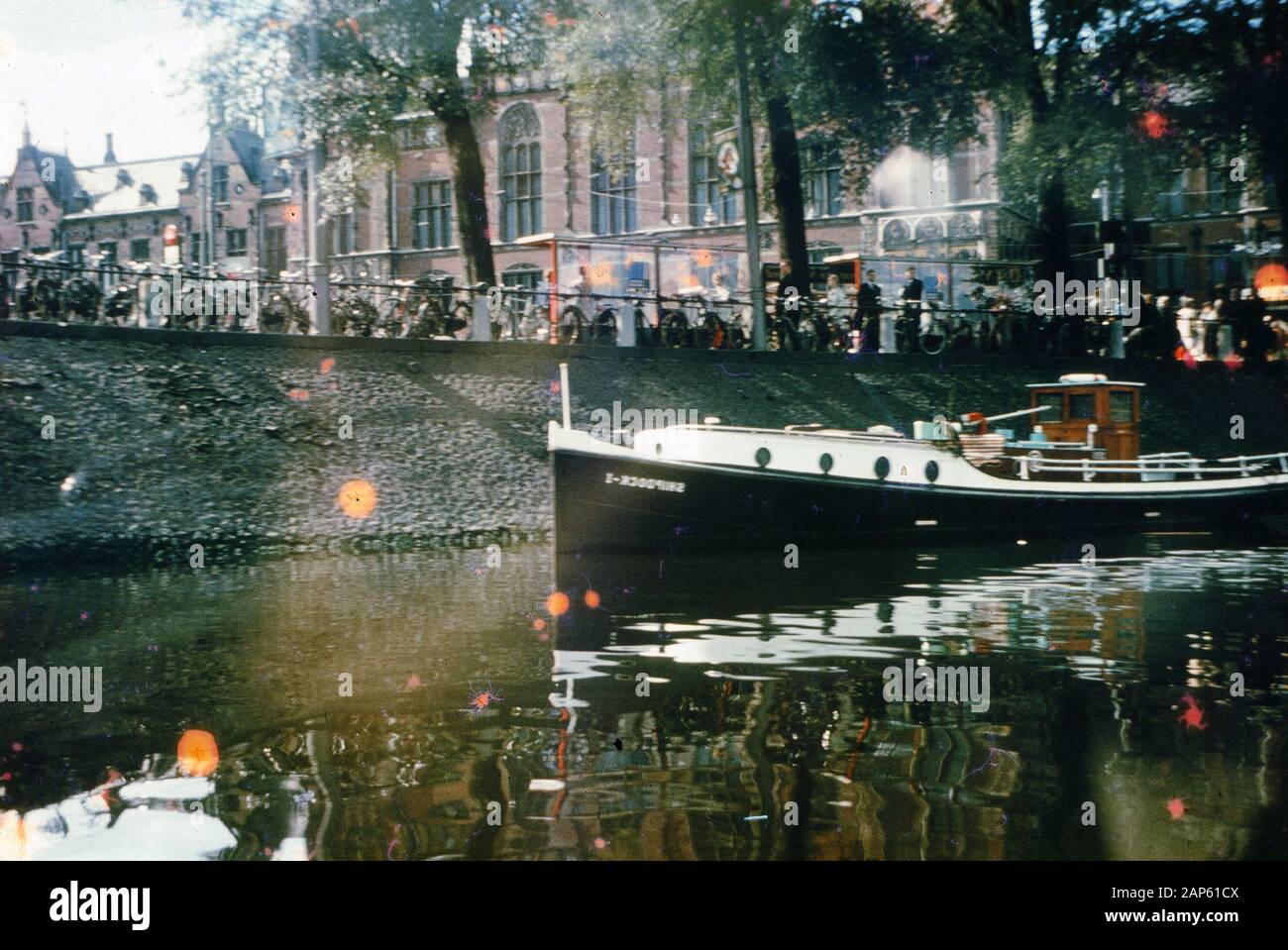 Photo vernaculaire prise sur un film analogique de 35 mm transparent, qui est censé représenter les personnes qui naviguent sur un bateau blanc sur l'eau pendant la journée sur le canal, 1965. Les principaux sujets/objets détectés sont l'eau, le bateau, la ville, la réflexion, le véhicule et le tourisme. () Banque D'Images