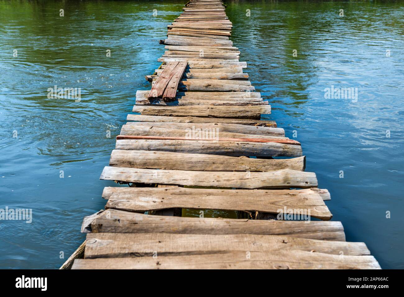 Vieux pont en bois à travers la rivière avec des arbres verts sur les rives Banque D'Images
