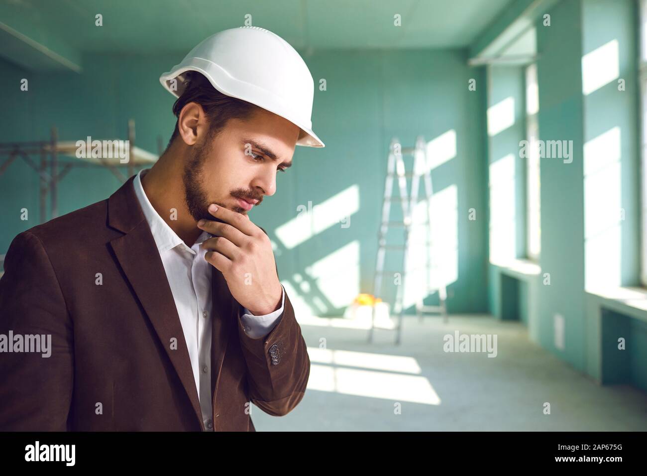 Builder contremaître dans un casque blanc surpris en état de choc sur un site de construction à l'intérieur Banque D'Images