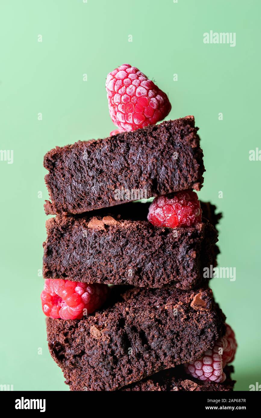 Gros plan chocolat brownie dans une pile de baies surgelées sur fond vert. Délicieux gâteaux de cacao. Pile de brownies et de framboises. Dessert au chocolat. Banque D'Images