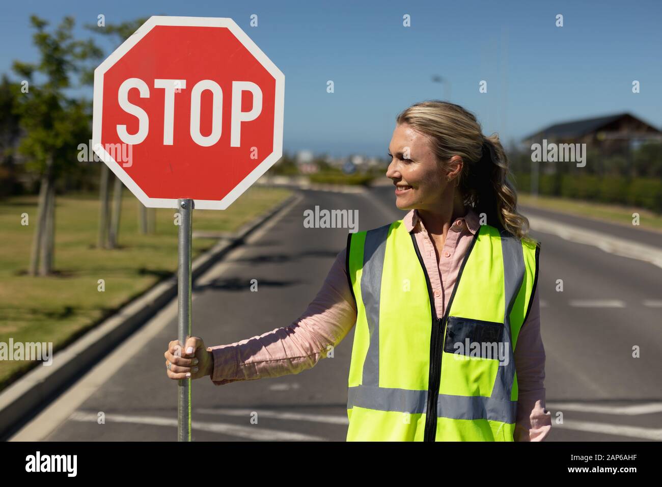 Femme portant un gilet haute visibilité et tenant un panneau stop Banque D'Images