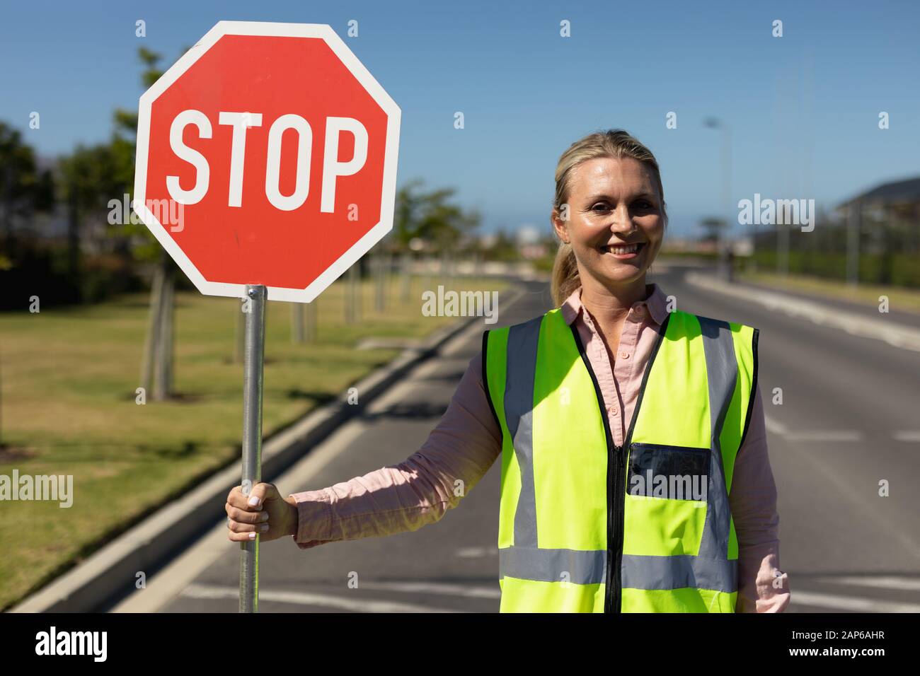 Femme portant un gilet haute visibilité et tenant un panneau stop Banque D'Images