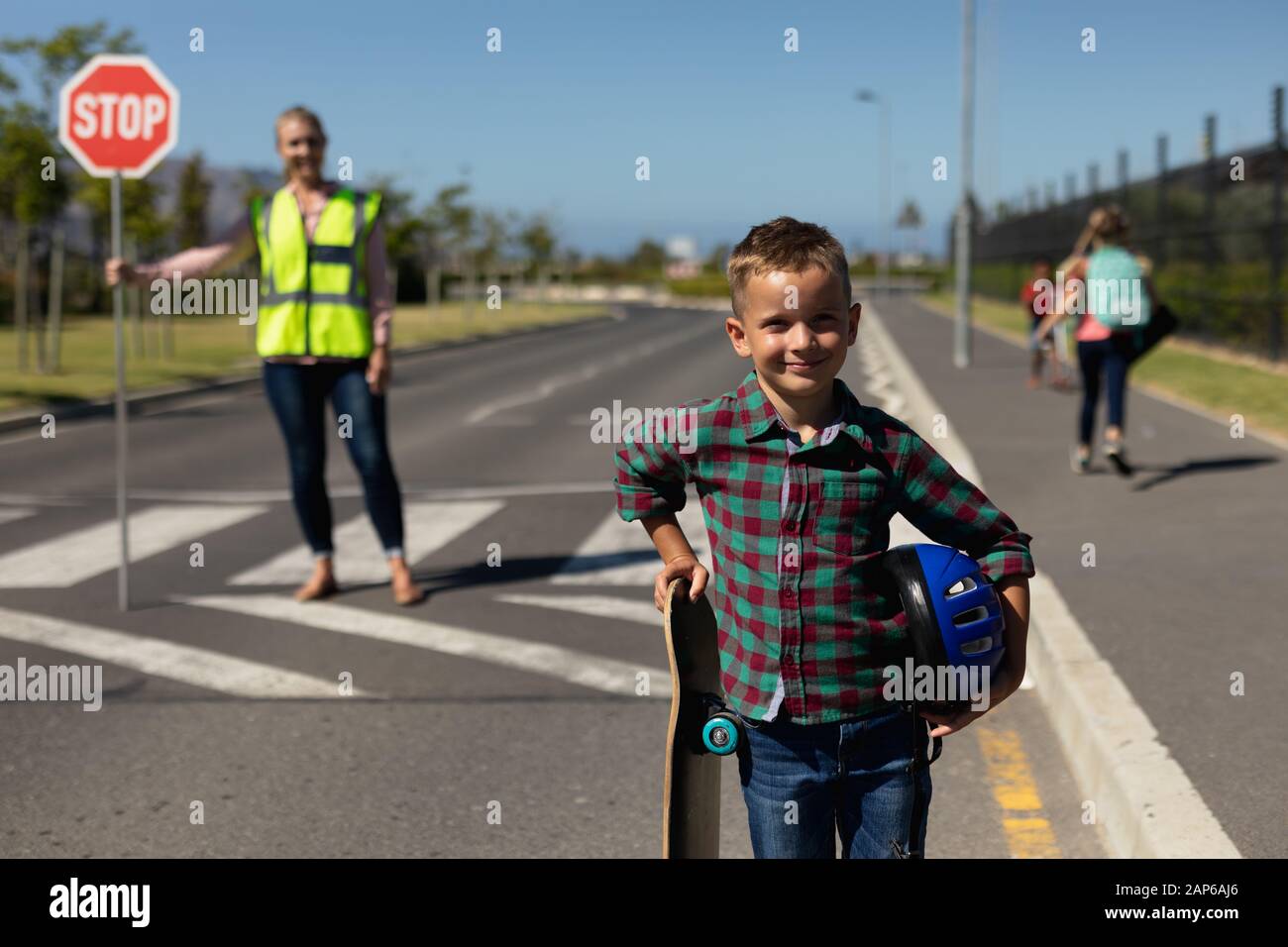 Un écolier debout sur la route tenant un skateboard et un casque Banque D'Images