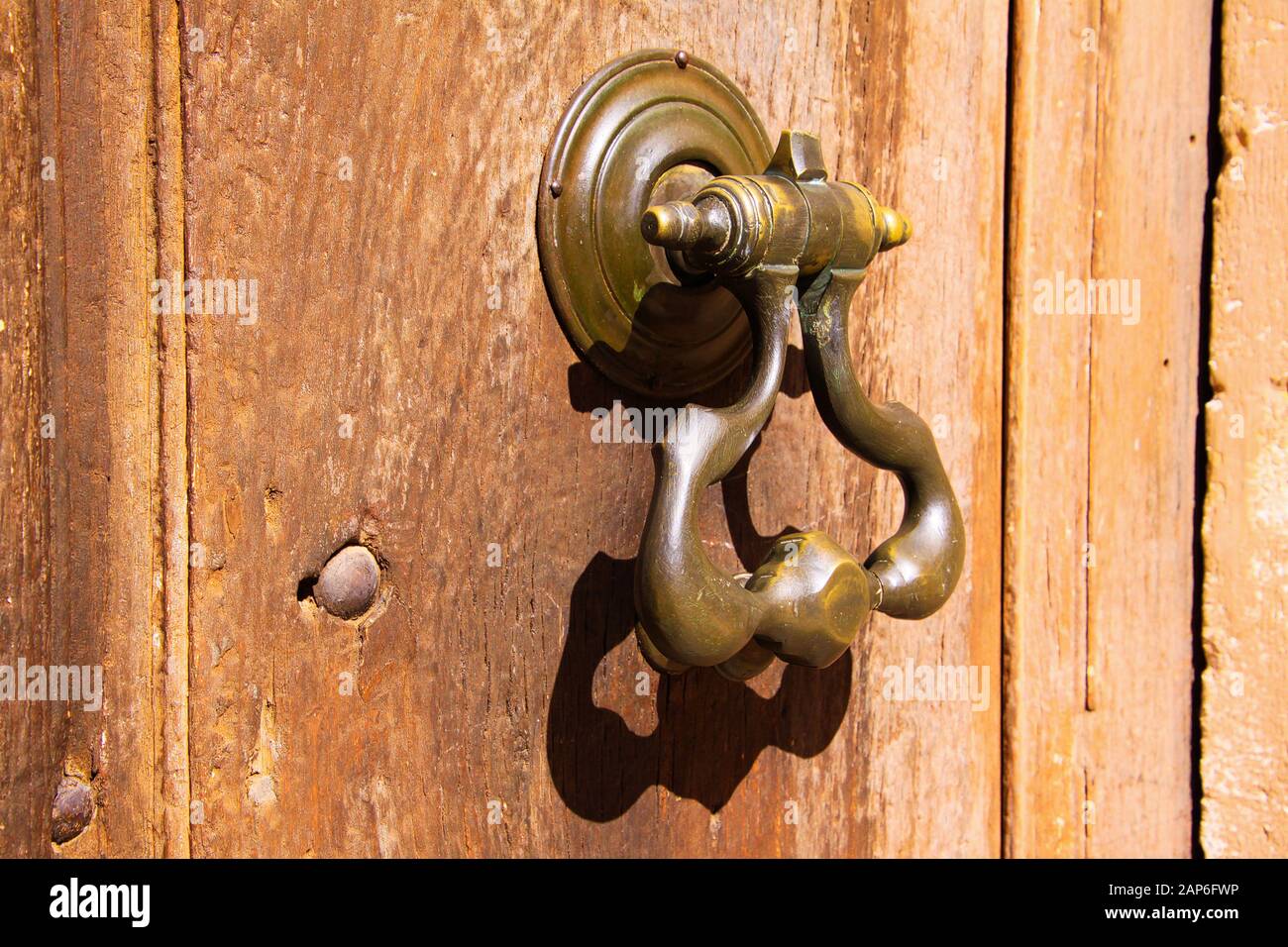 Gros plan sur le knocker de porte de fer en métal antique sur l'entrée en bois dans un soleil naturel lumineux - Provence, France Banque D'Images