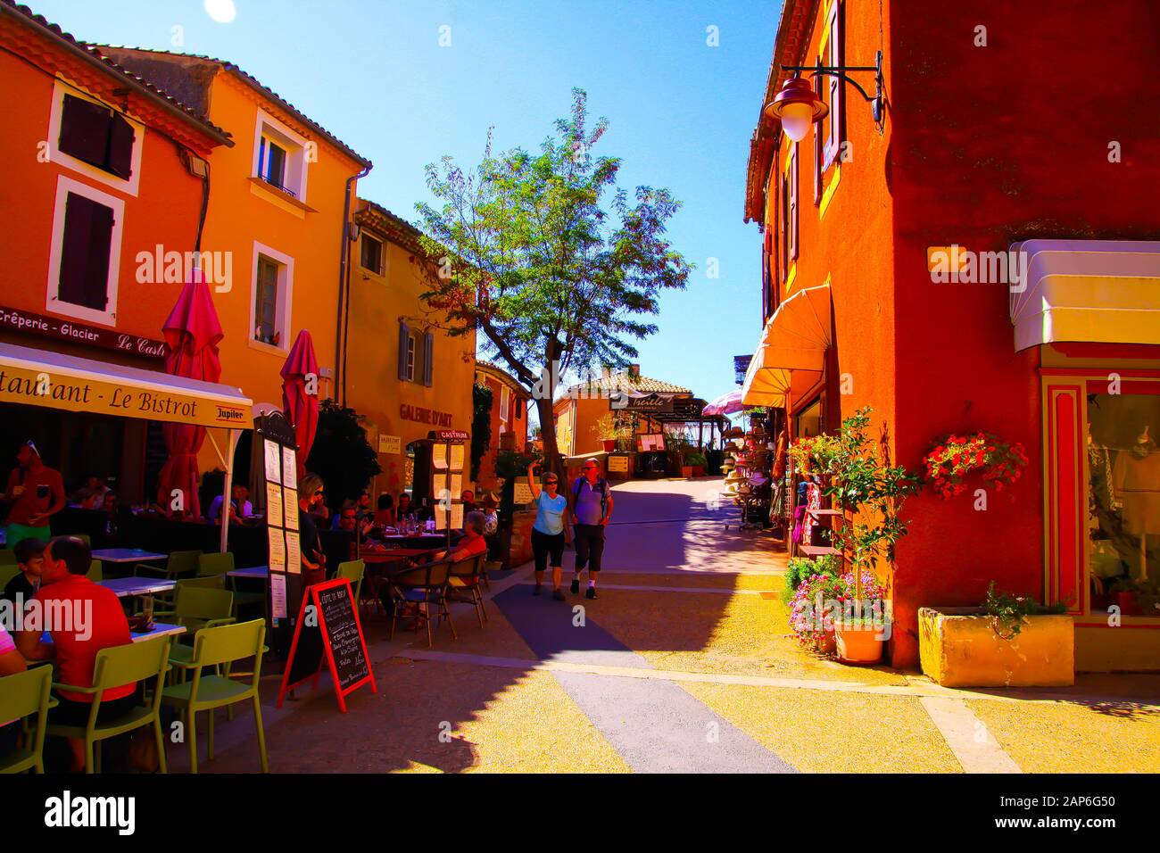 Roussillon En Provence, France - 2 Octobre. 2019: Vue sur la place avec restaurant (bistrot) sur des maisons à façade rouge contre le ciel bleu le jour ensoleillé Banque D'Images