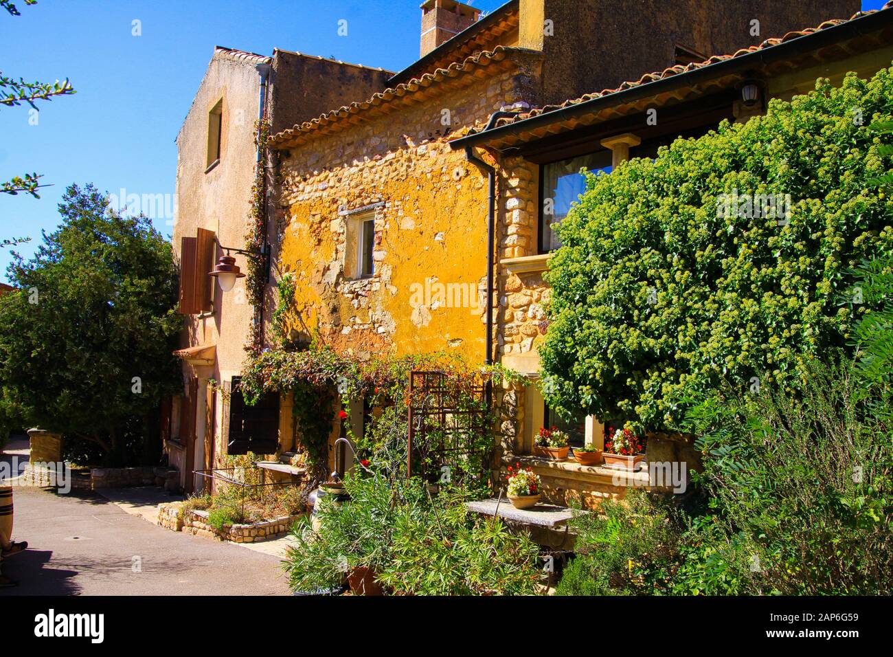 Roussillon En Provence, France - 2 Octobre. 2019: Vue sur la maison rurale en pierre jaune avec arbres, pots de fleurs et arbres le jour ensoleillé Banque D'Images