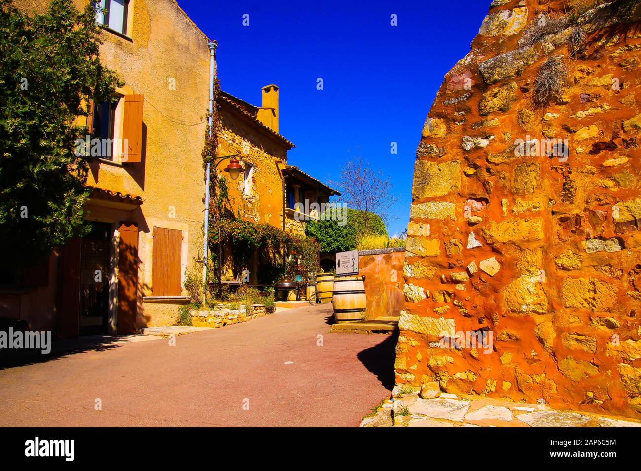 Roussillon En Provence, France - 2 Octobre. 2019: Vue au-delà de la forteresse jaune ocre mur de pierre naturel sur la rue avec des maisons méditerranéennes françaises agai Banque D'Images