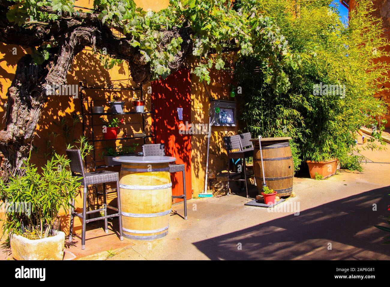 Roussillon En Provence, France - 2 Octobre. 2019: Vue sur la maison méditerranéenne d'ocre rouge avec de la vigne grimpant la façade, des tonneaux de vin et des arbres en soupir Banque D'Images