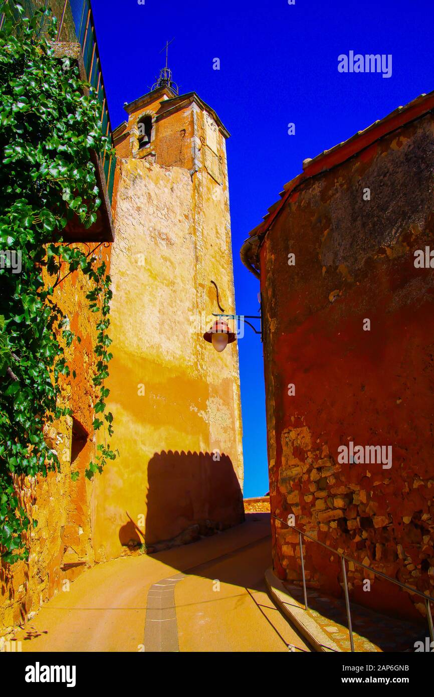 Vue à l'étage sur les marches et allée étroite sur la tour de l'église forteresse ocre contre le ciel bleu - Roussillon en Provence, France Banque D'Images