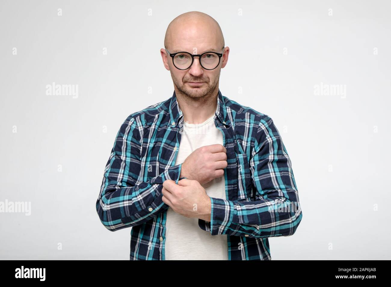 Un homme sérieux et sans rasé avec des lunettes se fixe un bouton sur un  brassard de chemise et regarde en toute confiance l'appareil photo Photo  Stock - Alamy