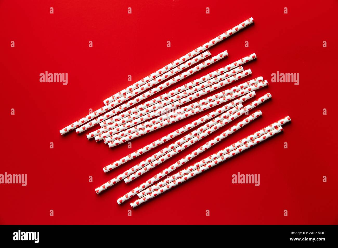Pailles en papier avec des coeurs sur fond rouge. Banque D'Images