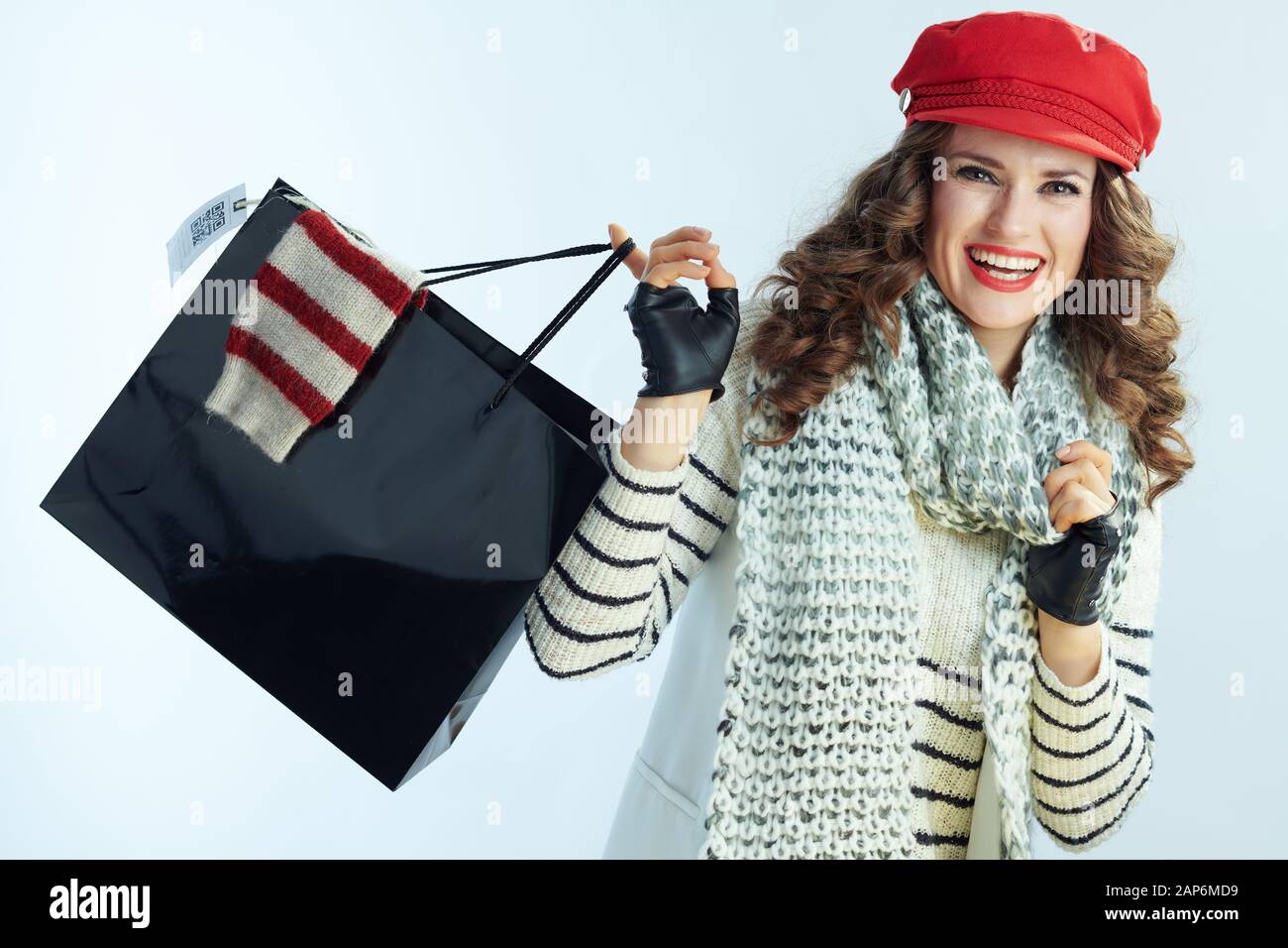 Portrait de femme élégante heureux avec de longs cheveux de brunette en pull, écharpe et red hat en noir panier avec pull acheté isolé sur w Banque D'Images