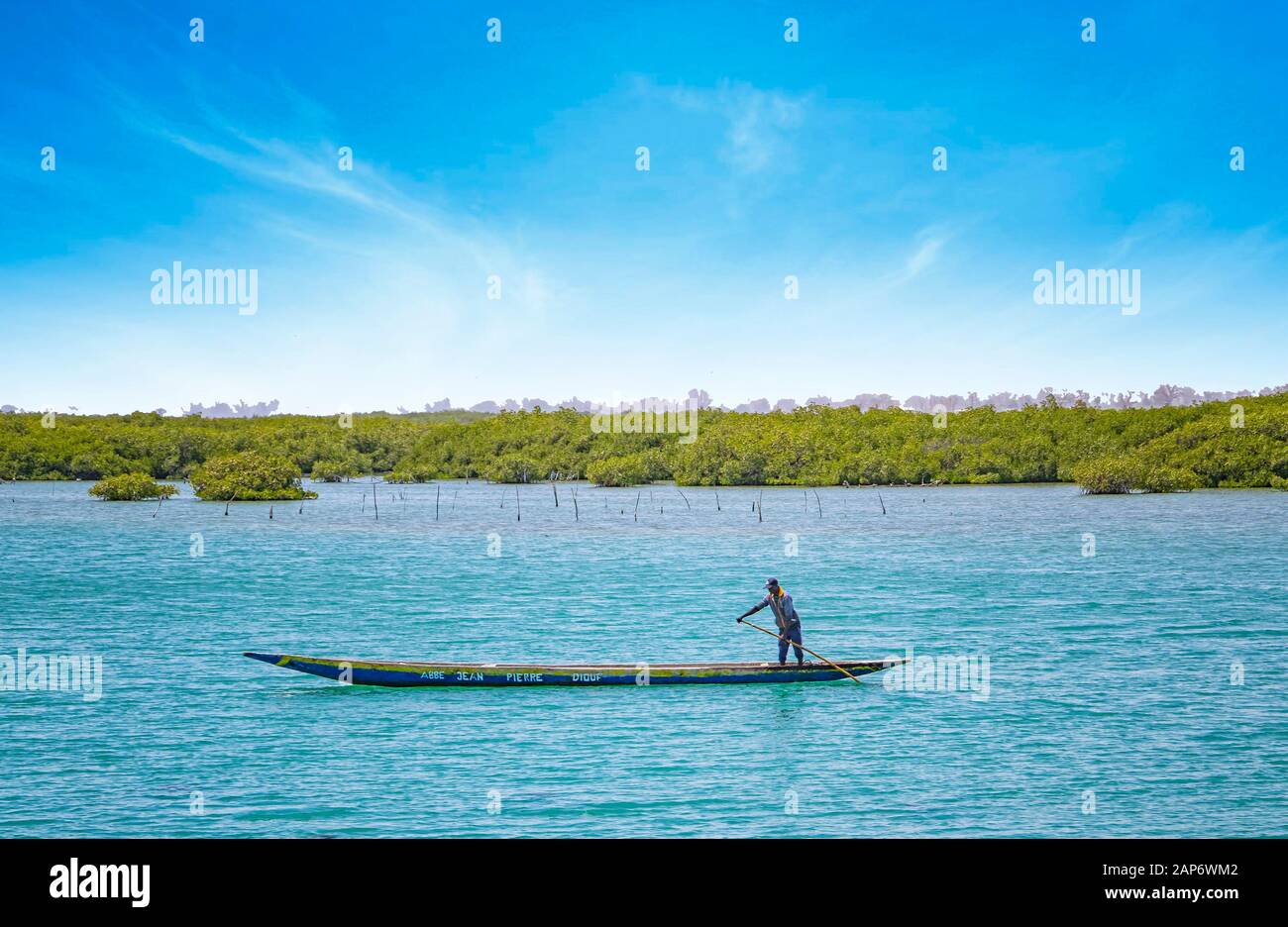 Fadiouth, Sénégal, AFRIQUE - 26 avril 2019 : un homme sénégalais non identifié mandate un canoë en bois typique dans un lagon marin et des poissons. Derrière lui sont Banque D'Images