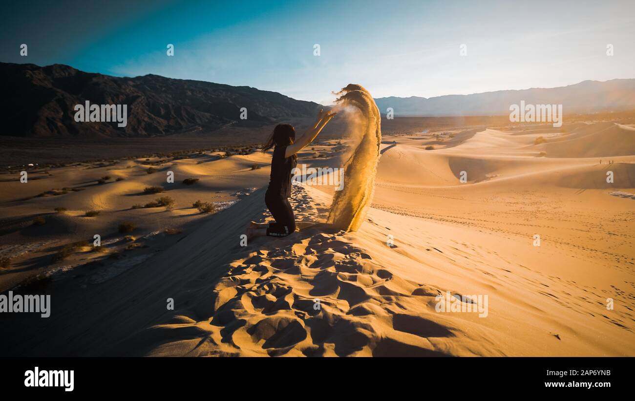 Fille jetant du sable sur les dunes de sable de Mesquite dans le Parc National de la Vallée de la mort, Californie, États-Unis Banque D'Images