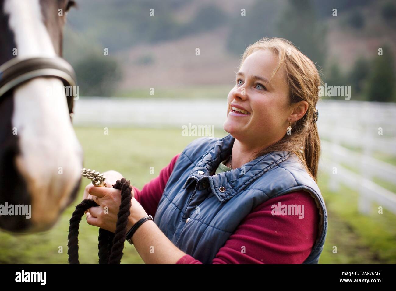 Jeune femme debout dans un enclos avec son cheval. Banque D'Images