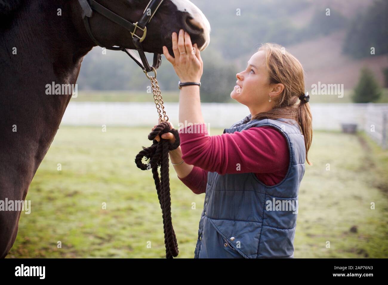 Jeune femme debout dans un enclos avec son cheval. Banque D'Images
