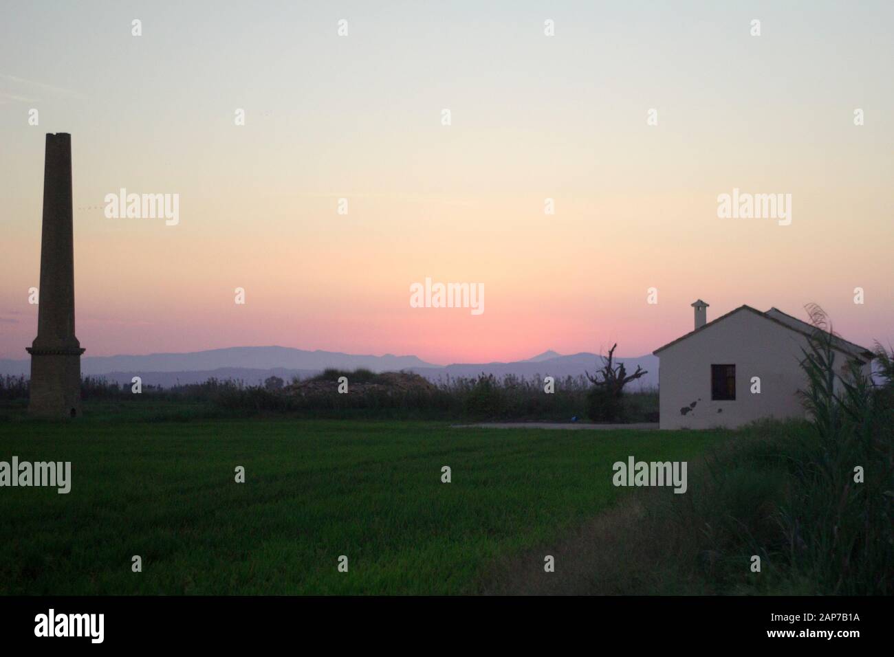 Grande tour et maison blanche avec champ vert dans les moments de coucher de soleil Banque D'Images