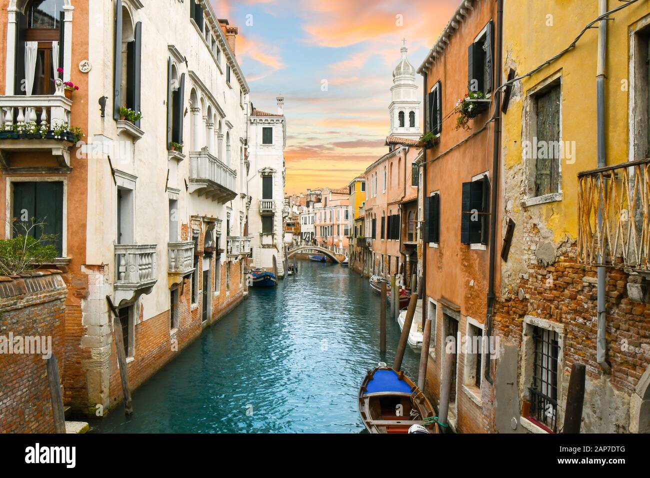 Un ciel coloré s'accorde avec les couleurs des murs médiévaux et du canal dans le centre historique de Venise, en Italie. Banque D'Images