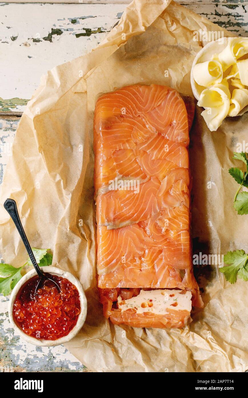Caviar de saumon rouge Bol en céramique et en terrine de saumon maison servi avec du beurre sur papier froissé plus vieille table en bois. Mise à plat, de l'espace Banque D'Images