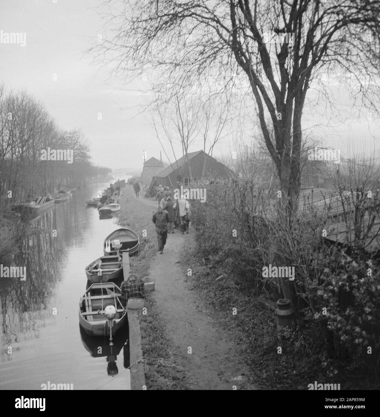 Club de cent (poissons); personnes marchant le long d'une rivière ou d'une rivière avec bateaux amarrés sur le rivage Date: 16 décembre 1965 mots clés: Canaux, rivières, bateaux à ramer, marcheurs Banque D'Images