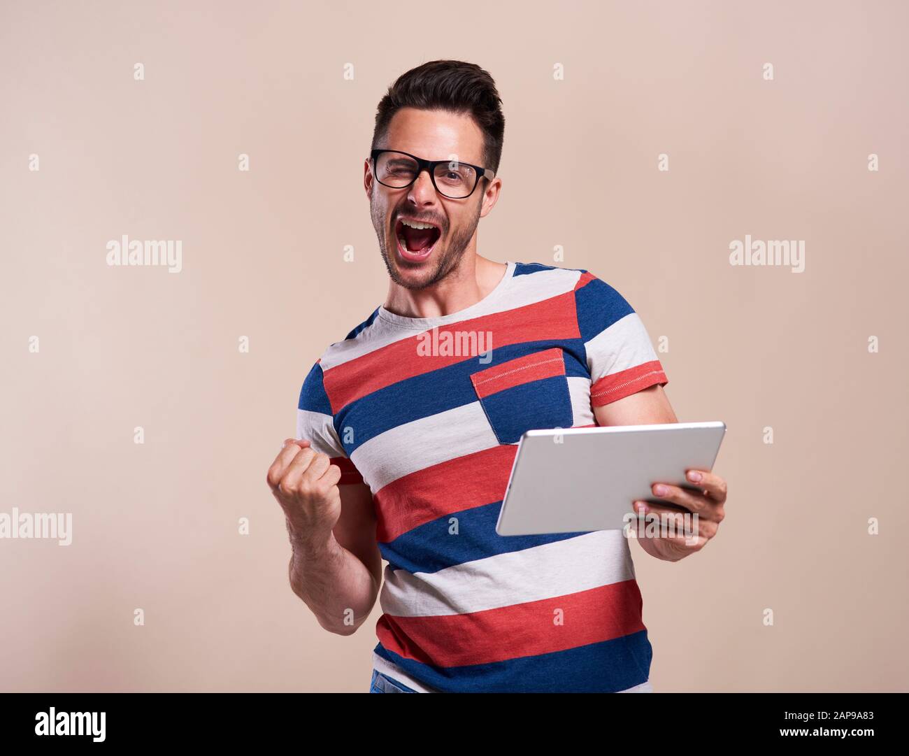 Homme excité avec une tablette en studio Banque D'Images