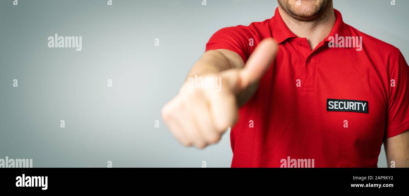protection de service de sécurité en uniforme rouge avec le pouce vers le haut sur fond gris. espace de copie Banque D'Images