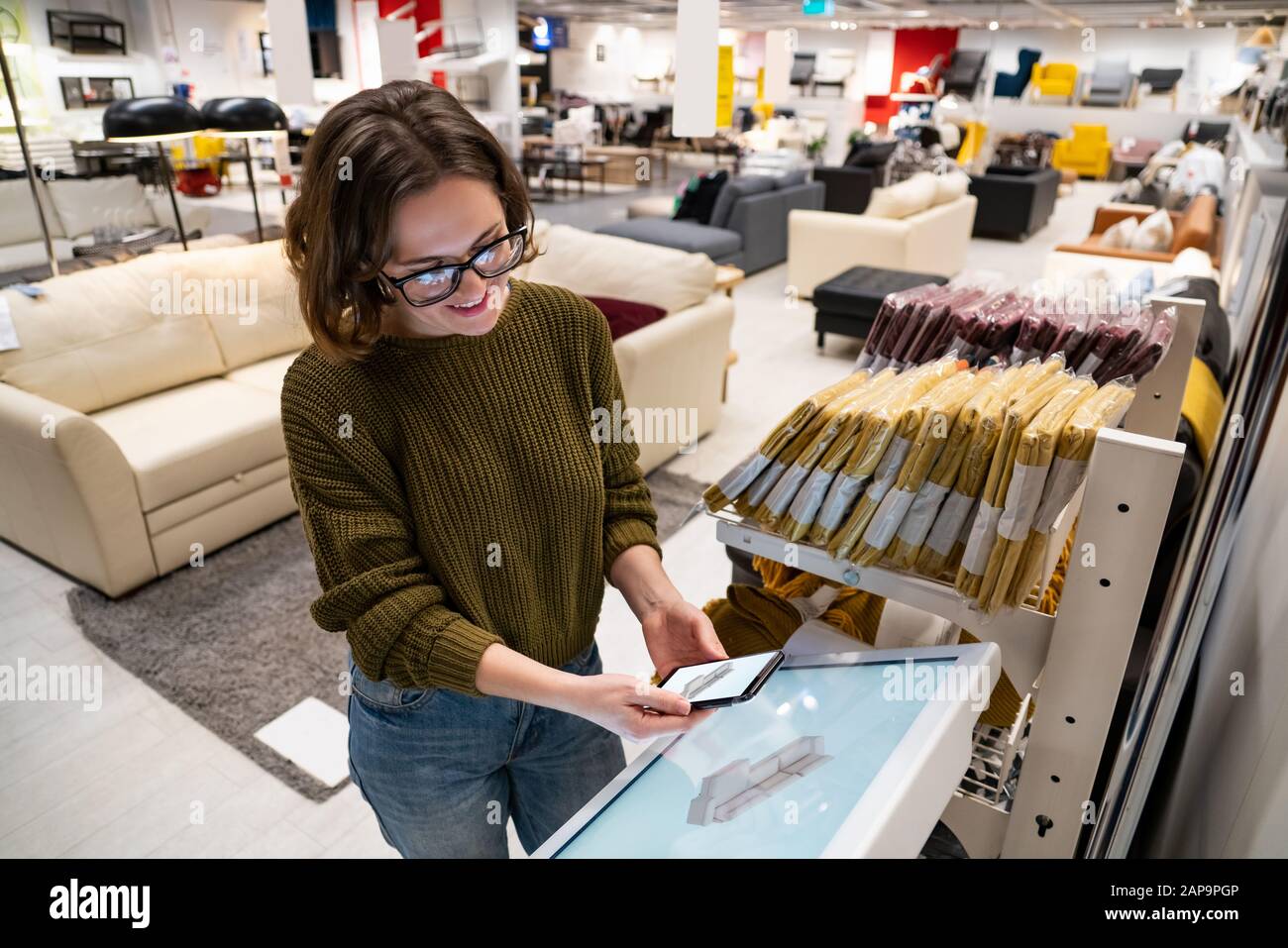 Une femme avec téléphone utilise un kiosque en libre-service dans le centre commercial Banque D'Images