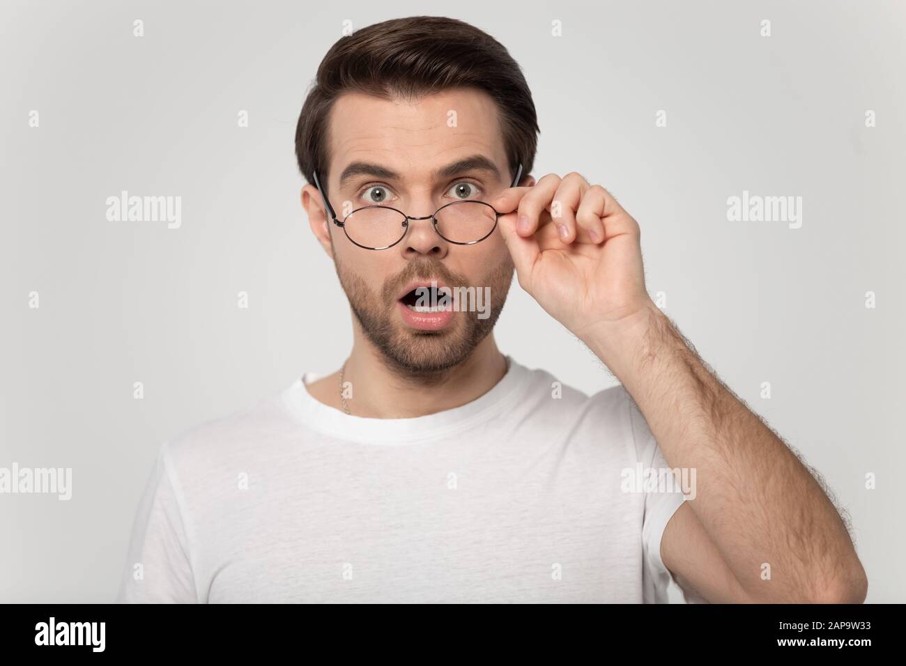 Un jeune homme a surpris l'homme qui regarde l'appareil photo, en prenant des lunettes. Banque D'Images