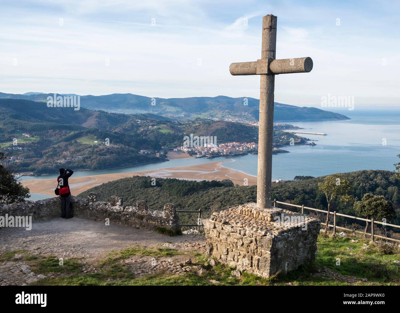 Randonneur photographiant l'estuaire d'Urdaibai du point de vue de San Pedro Atxarre à côté du monolithe croisé avec Mundaca et le cap Machicacho (Pays basque, Espagne) Banque D'Images